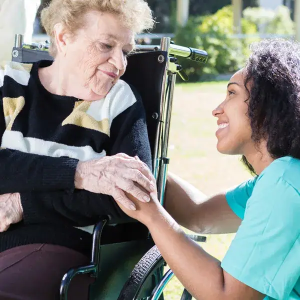 A carer holding hands with an elderly woman